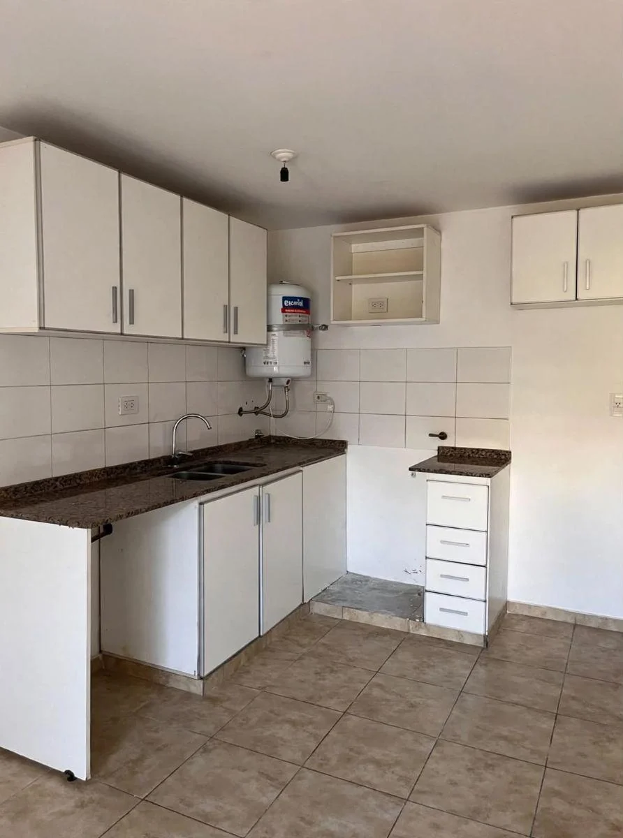 Cocina con mesada, bajo mesada, alacenas y termotanque.